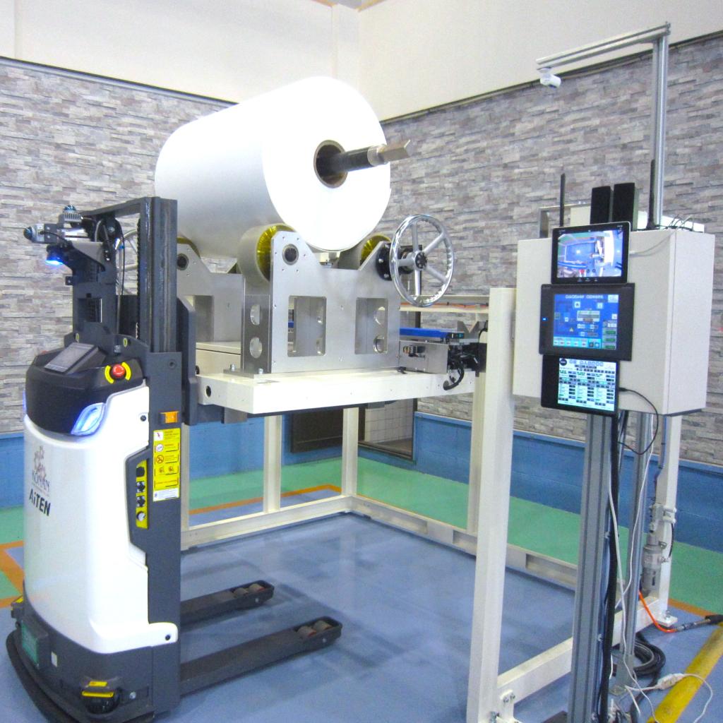 ロール状に巻き付けたフィルムシートなどの重量物を次の工程に正確に搬送する自動搬送・装着ロボット
