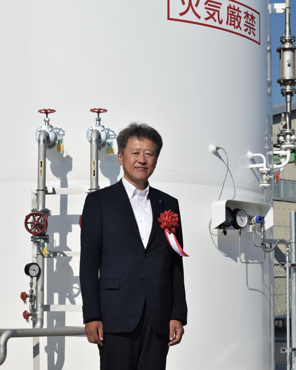 新しい水素設備の前に立つ堀内社長