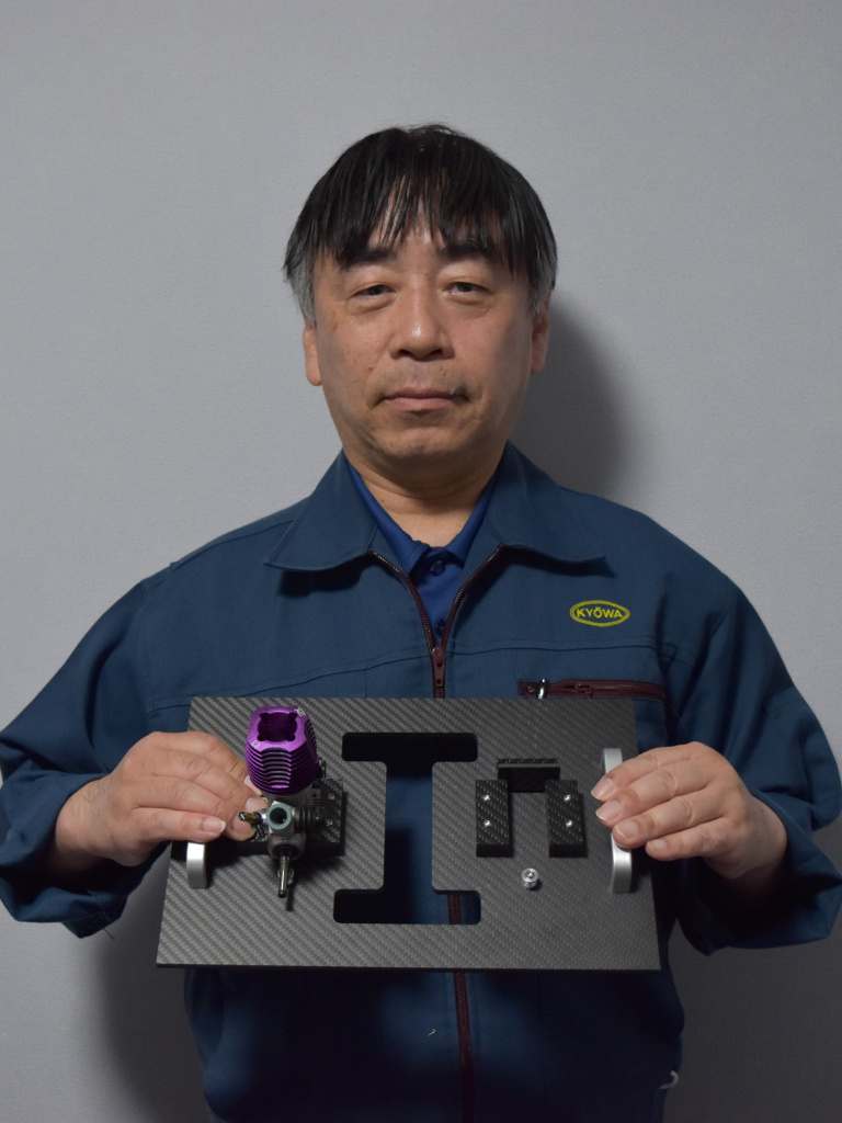 ＣＦＲＰ化したエンジン治具のミニチュアと、セミナー講師を務める大宮氏