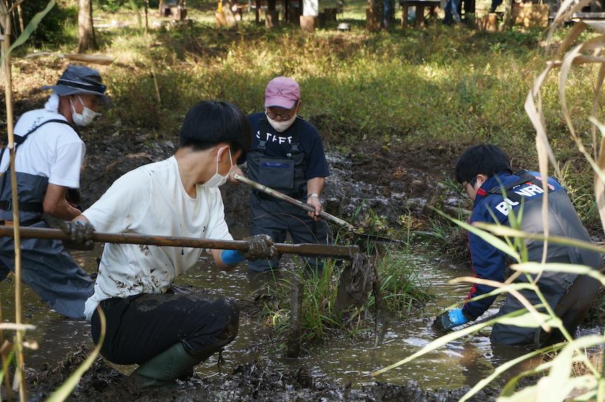 天覧山麓の溜池で、かい掘りエコツアーを楽しむ泥まみれの参加者