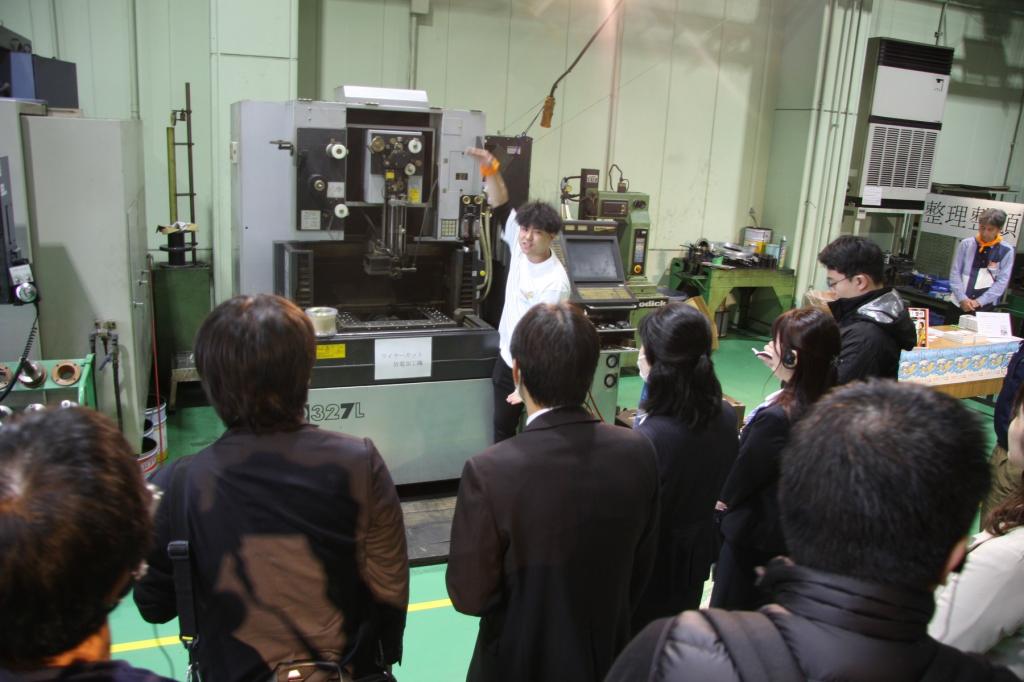 工場見学ツアーで製造工程の説明を熱心に聞く参加者