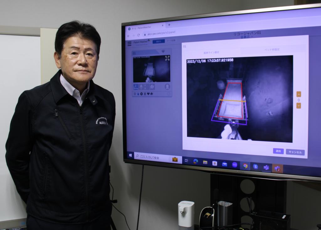 見守りシステムのペイシェントウォッチャーはカメラ画像を解析してベッドからの離床や起床を検出できる。ディスプレー左は木田社長